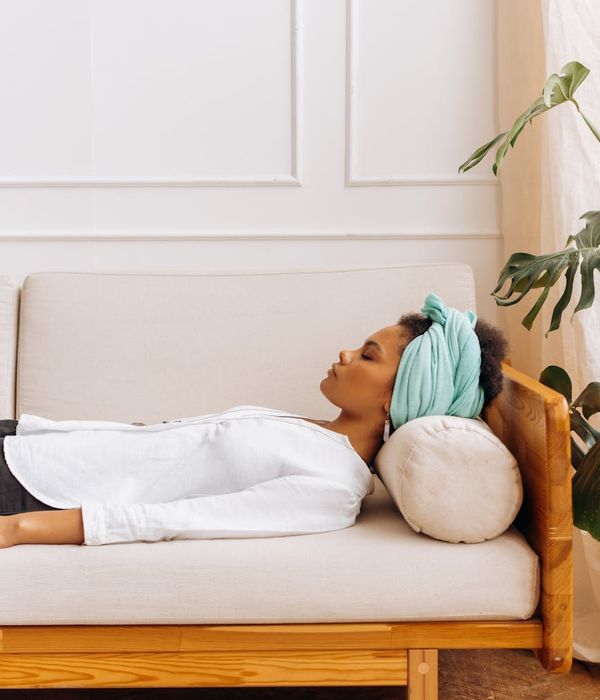 Woman in a calm yoga pose in a softly lit, minimalist room.